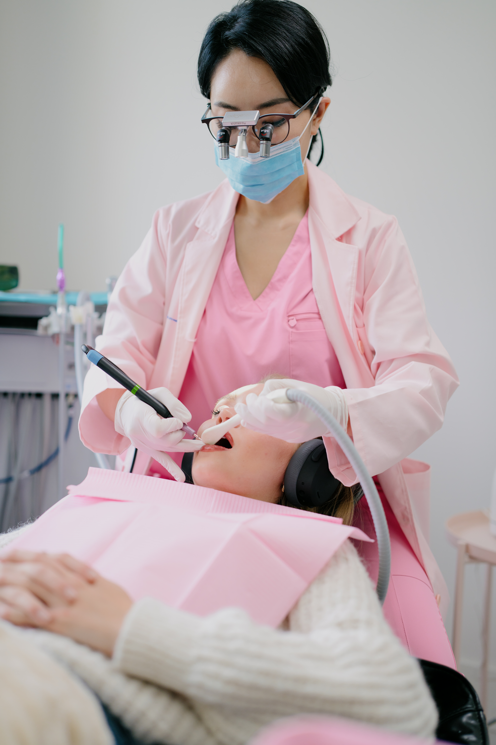 A dental hygienist in pink scrubs performing a gentle GBT cleaning on a relaxed patient at Aviator